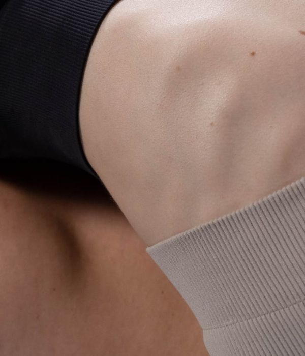 Man performing a balancing exercise on one leg in a calm, minimalist environment.